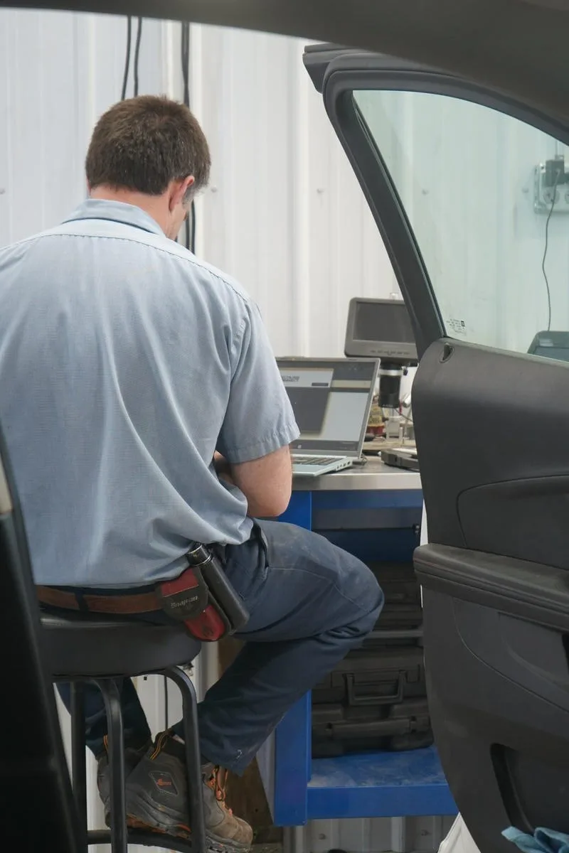Technician accessing dashboard wiring for electrical diagnosis